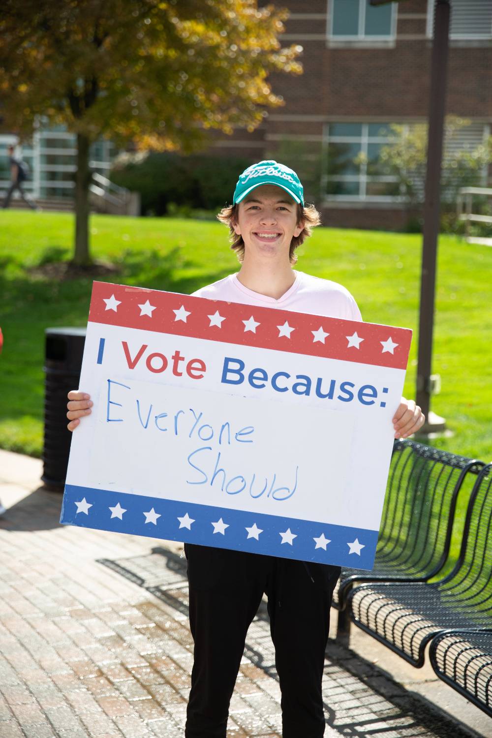 Student holding sign titled "I vote because: Everyone should"